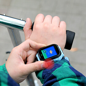 Smartwatch dla dzieci w kolorze niebieskim z funkcją telefonu na ręku dziecka, które naciska przycisk sygnał SOS